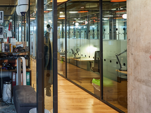 Contemporary open style shared workspace featuring glass walls and wooden floors Zoom background