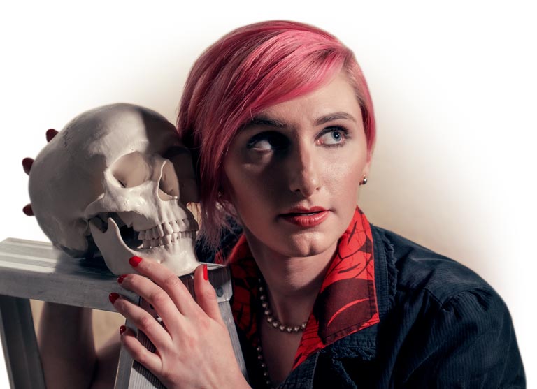 Kate Durr in pink hair and red dress poses with a model skull