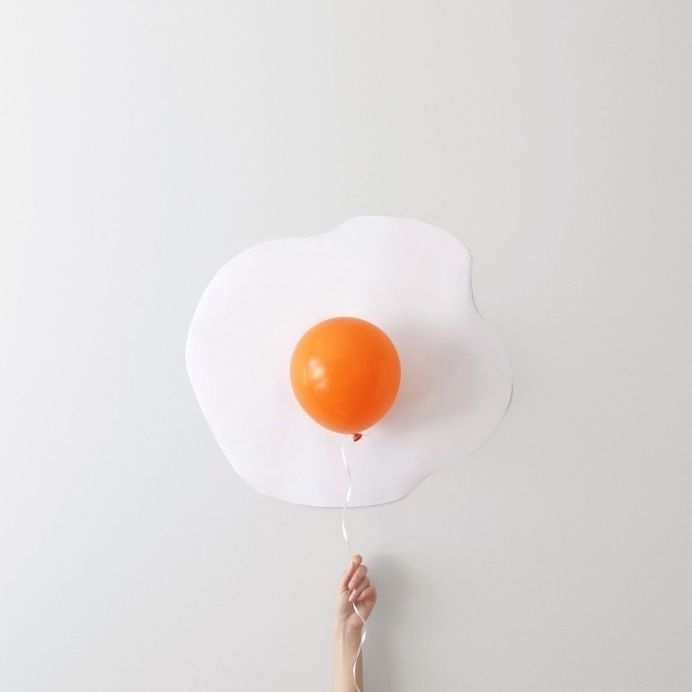 Person holding a balloon against a wall to make it look like an egg