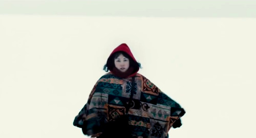 A screenshot from the movie 'Kumiko The Treasure Hunter' of Kumiko (played by Rinko Kikuchi) wrapped in a patterned quilt in the snow.