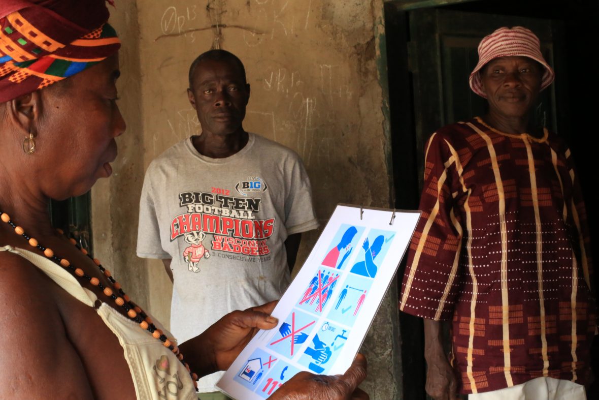 A resident of Bassaia Village Tonkolili District Northern Sierra Leone looks at a COVID-19 poster distributed by Concern Worldwide after a prevention training session.