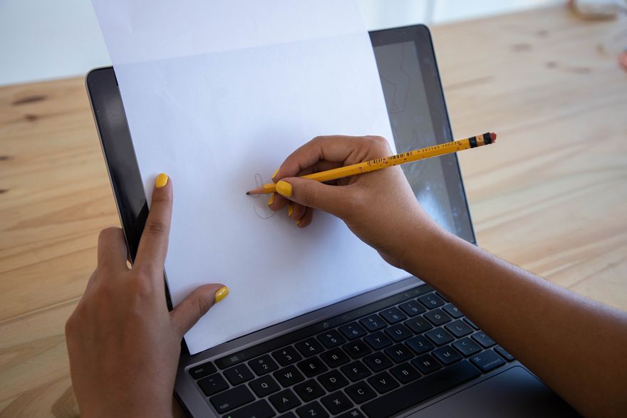 during an icebreaker, a woman draws a shape with a pencil on a piece of paper placed on top of her laptop screen