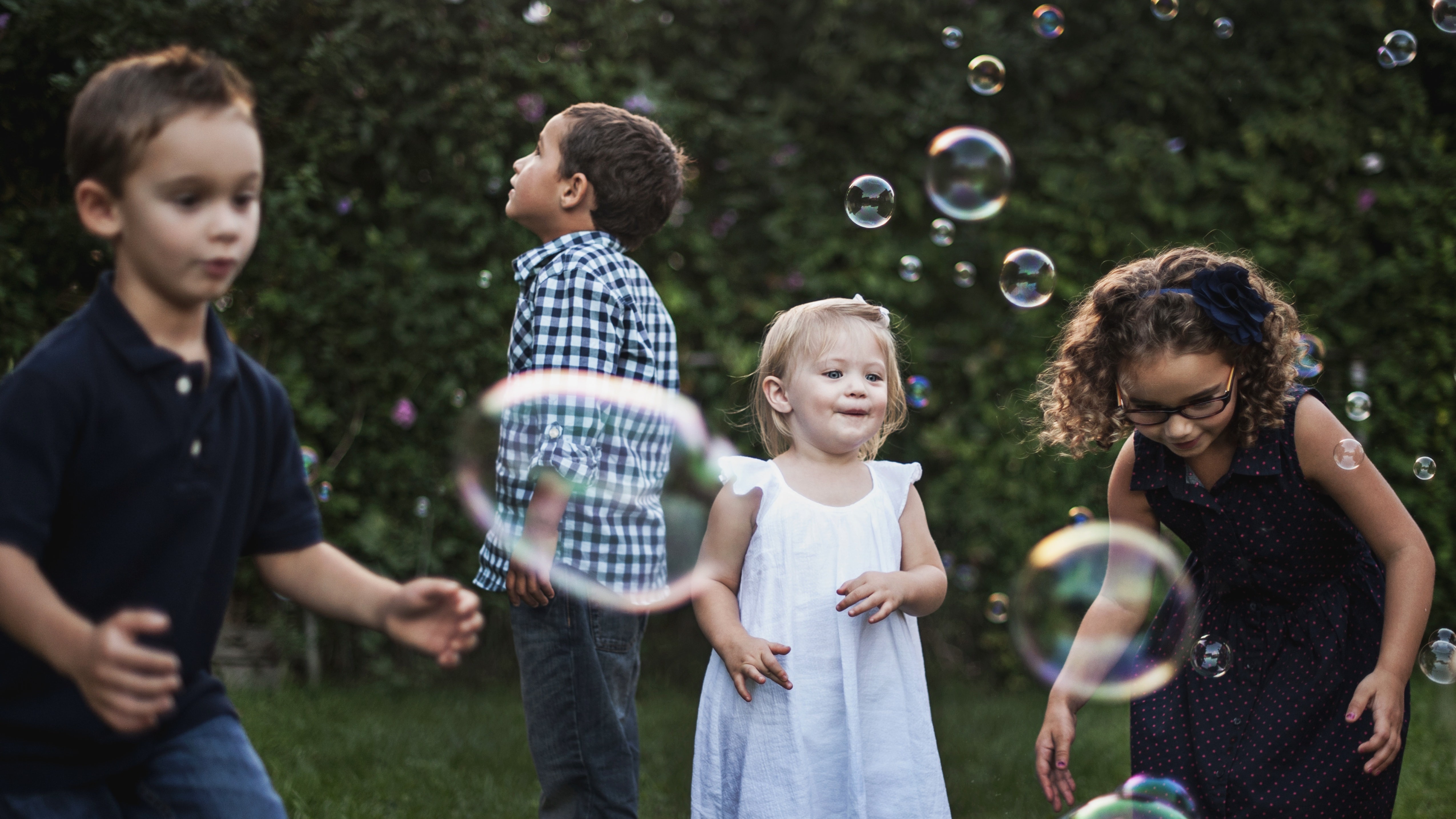 Four children chasing bubbles in a school yard