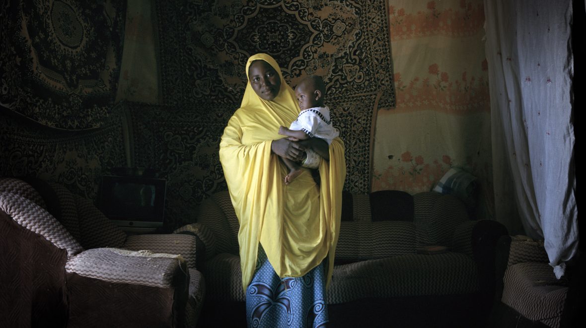 Nigerien woman stands inside her home
