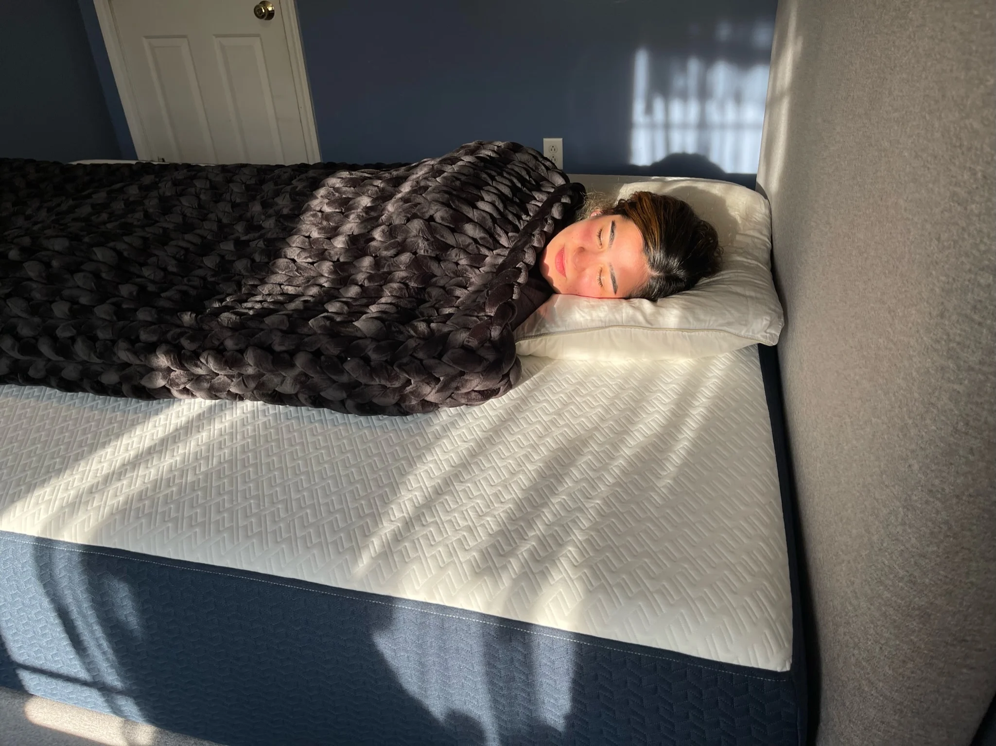a reviewer taking a nap with hush knit weighted blanket in sleepiverse studio