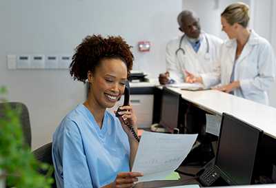 A healthcare professional talking on the phone while reviewing a document