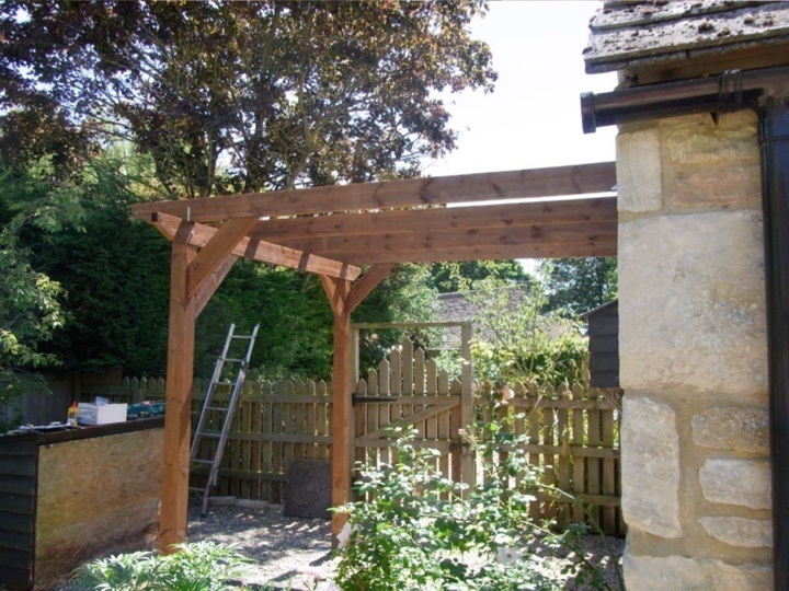 A leon to pergola set against the side of a stone-built house