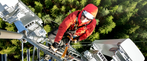 photo of man climbing communications tower