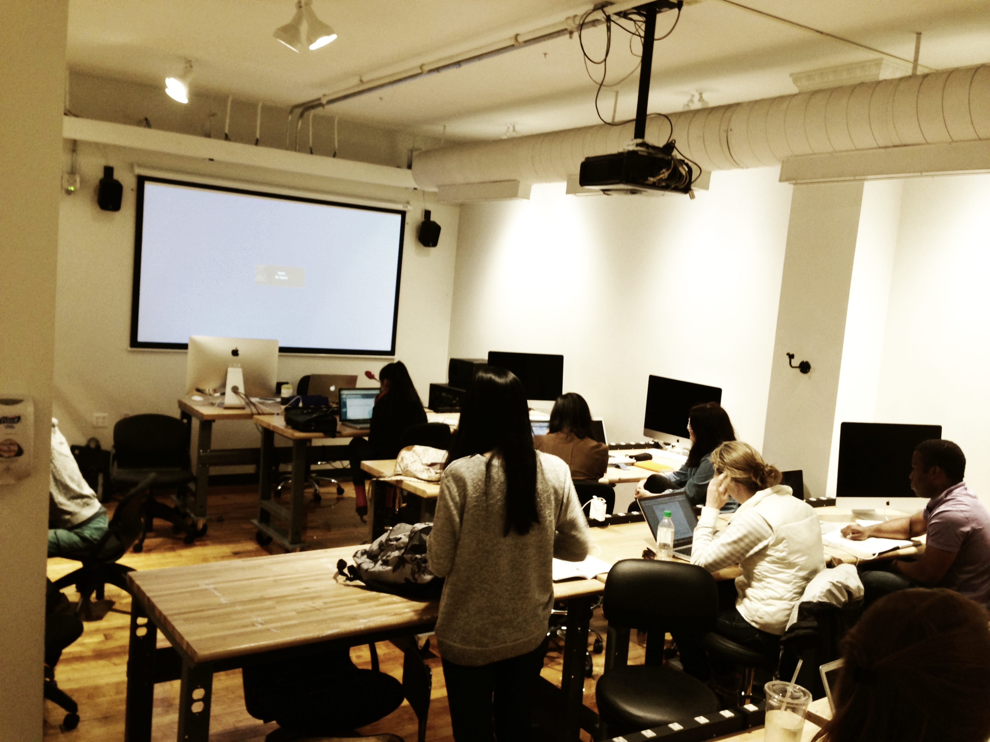 wide shot of my classroom at RISD: projector screen in front, rows of students at high desks with laptops