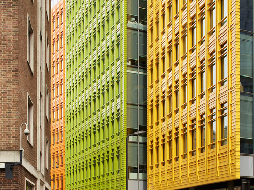 Bright green orange and yellow coloured city buildings with many windows opposite red brick building Zoom background
