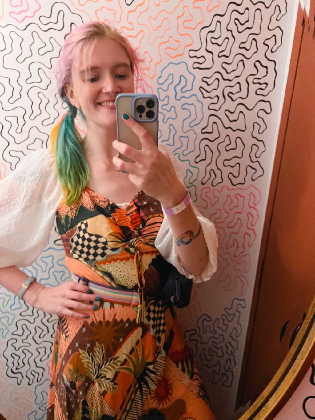 Mirror selfie of Beth wearing a fun Farm Rio dress over some puffy sleeves, with a fanny pack