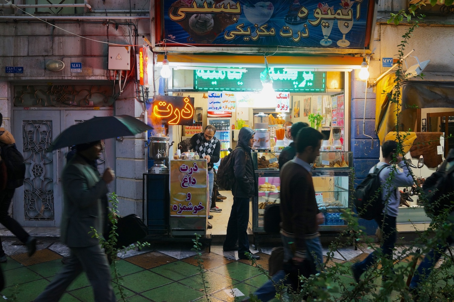 Street vendor with a neon sign that reads “corn”, a common street food in Tehran