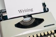 a retro typewriter with a piece of paper containing a single word, writing