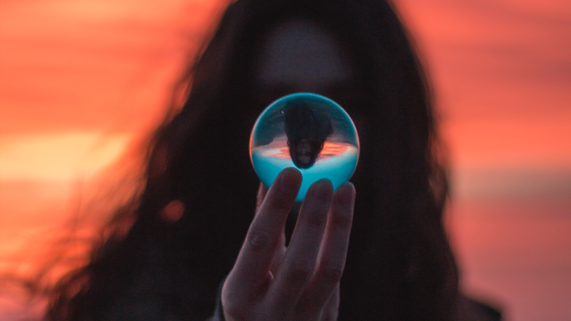 girl in sunset holding a glass globe in front of her