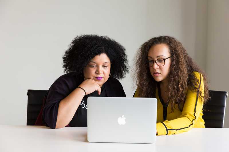Two women working together on a laptop computer.