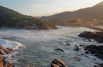 Vista de dentro do mar para praia pegando pedras no meio do mar e montanhas ao fundo