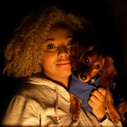 Portrait of Jade and her pup Sprout lit by a warm glow.