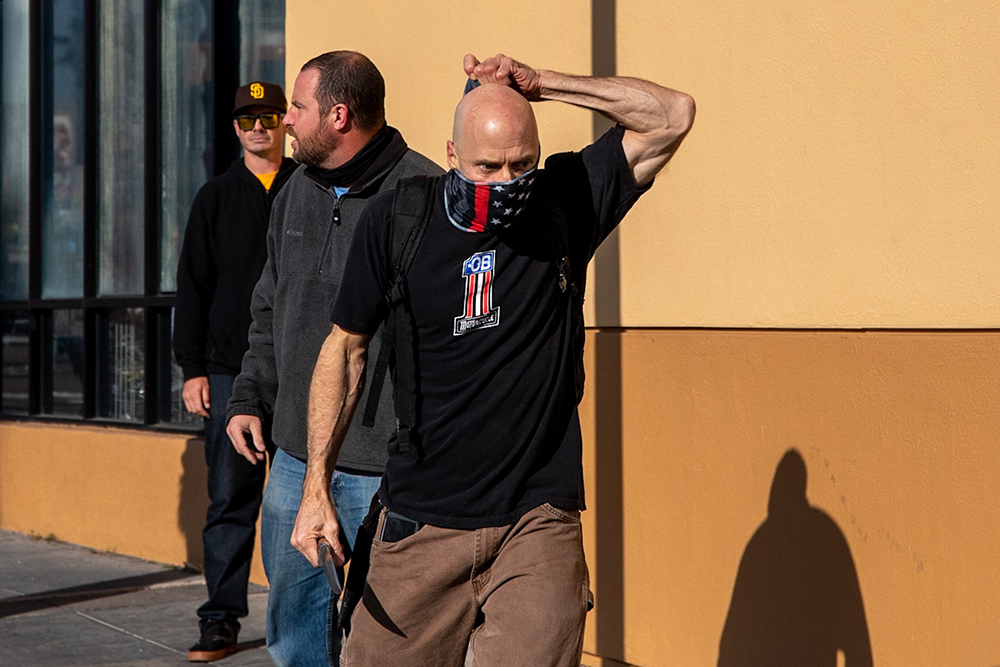 Neo-Nazi who brandished a knife straightens his gaiter and walks toward antifascist counter-protestors.