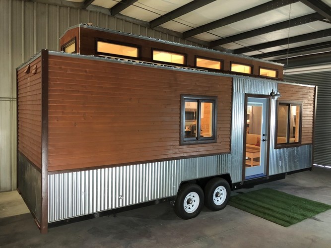 External view of this tiny home on wheels, showing 8 windows and the windowed front door. External view of this tiny home on wheels, showing 8 windows and the windowed front door.