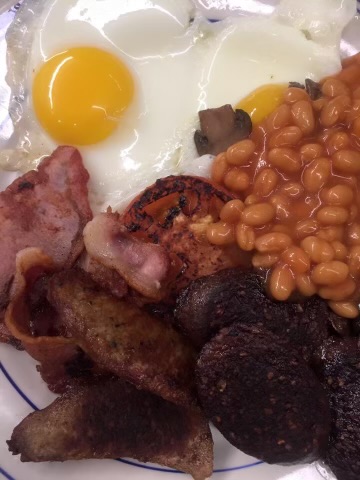 A picture of a full english breakfast, beans, eggs, bacon, and blood sausage