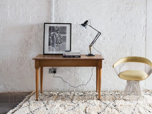 Wooden table with black adjustable lamp and framed drawing of a baby hippo next to retro cream chair Skype background