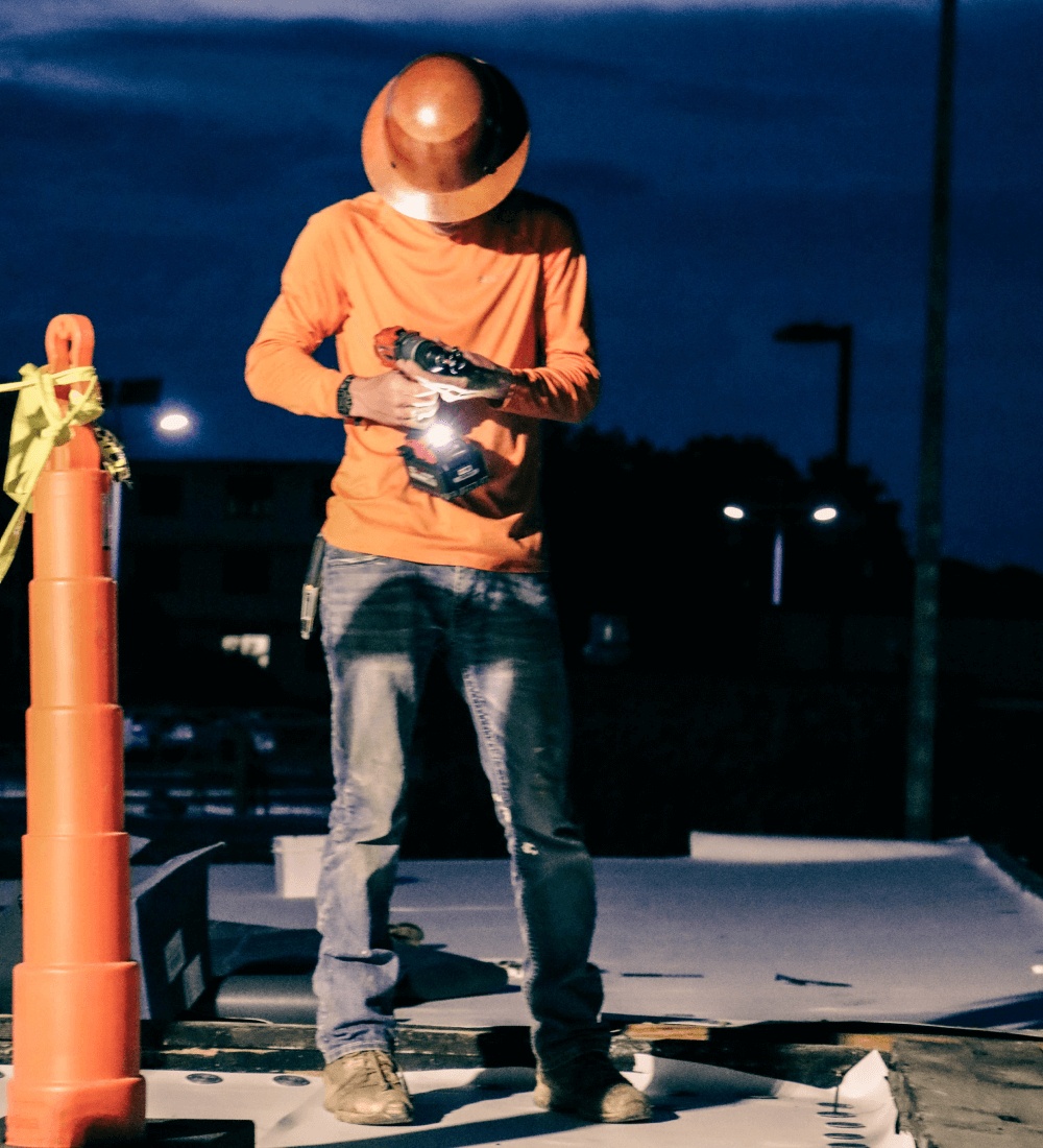 A worker at night on a roof
