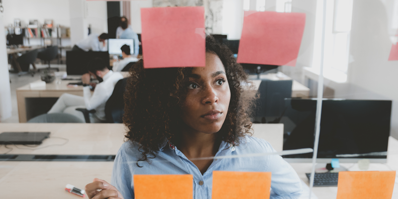 A woman designer looking pensively at some post-it notes A woman designer looking pensively at some post-it notes