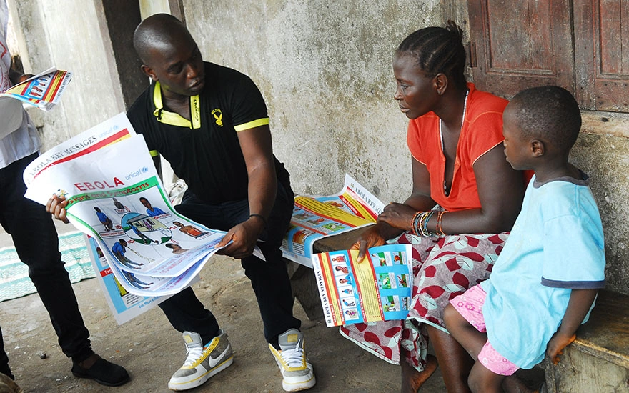 A person delivering information about the ebola virus to an adult and a child.