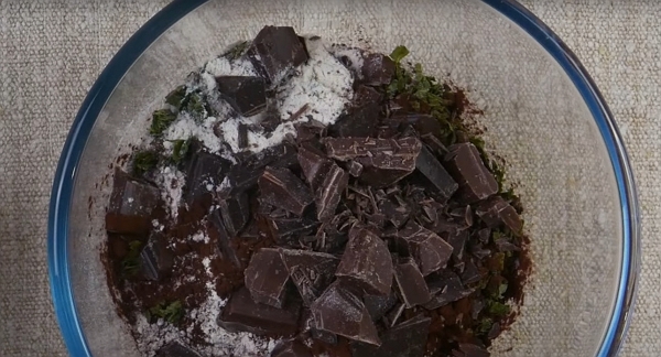 Un bol de cuisine avec le chocolat, des feuilles en morceaux sur de la farine