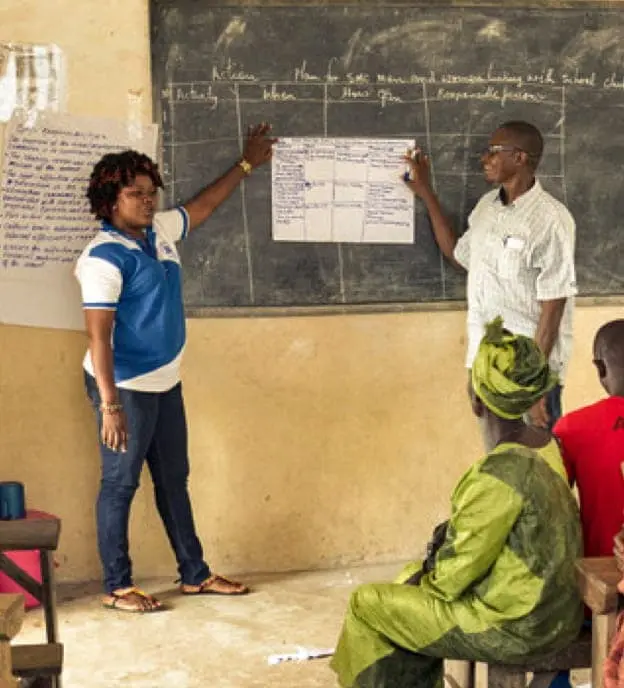 Pikin To Pikin staff member Victoria Squire leads a School Management Committee (SMC) training session in Makali Community, Tonkolili District, Sierra Leone.