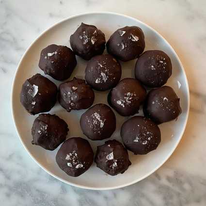 Melt the chocolate in a [double boiler](https://alwayseatdessert.com/how-to-melt-chocolate-in-a-double-boiler/). Dip the truffle centers into the chocolate and roll around to coat. Set aside to cool on a sheet tray lined with parchment paper. Sprinkle with flaky salt or pecan crumbs.
