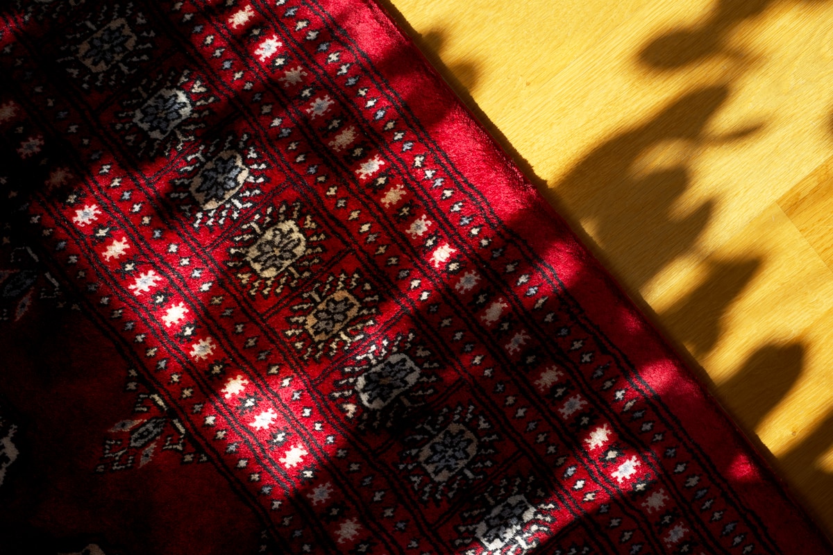 A red, sorry maroon, rug against oak wood flooring.