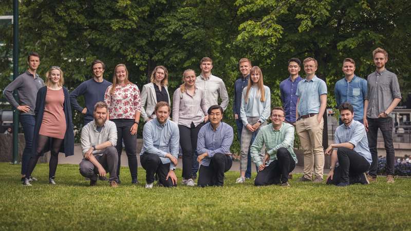 Bilde av 18 studenter som poserer til et gruppebilde i to rader på gresset. Det er fem kvinner og resten menn. Alle har lys hud.