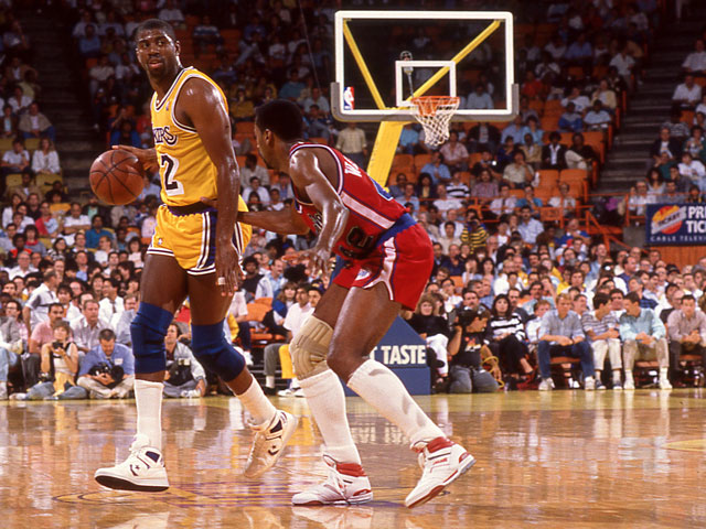 NBA player, Magic Johnson dribbling by a defender on the court