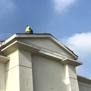 man on top of a commercial building roof being painted
