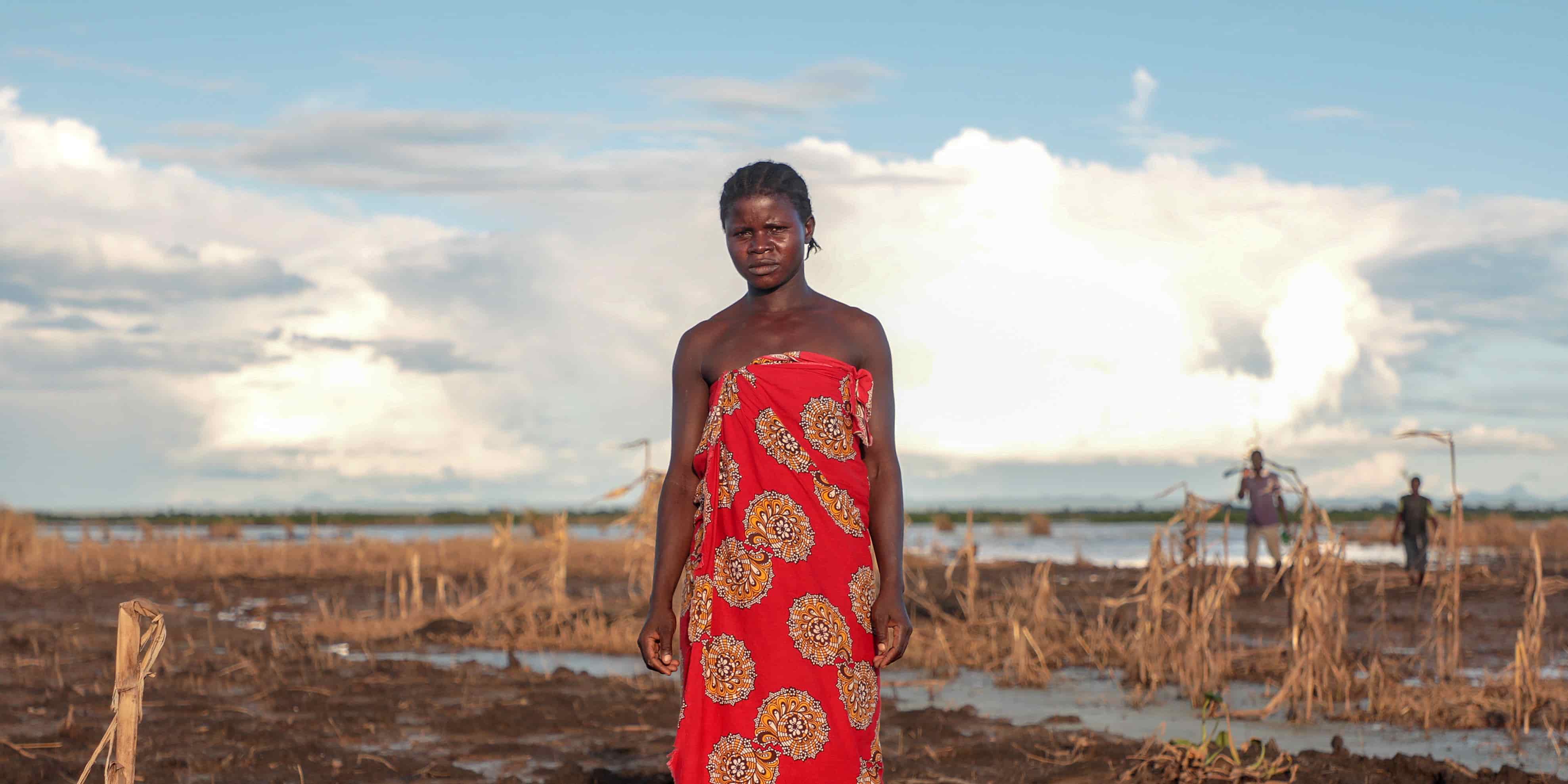 A Malawi farmer inspects what is left of her field after flooding