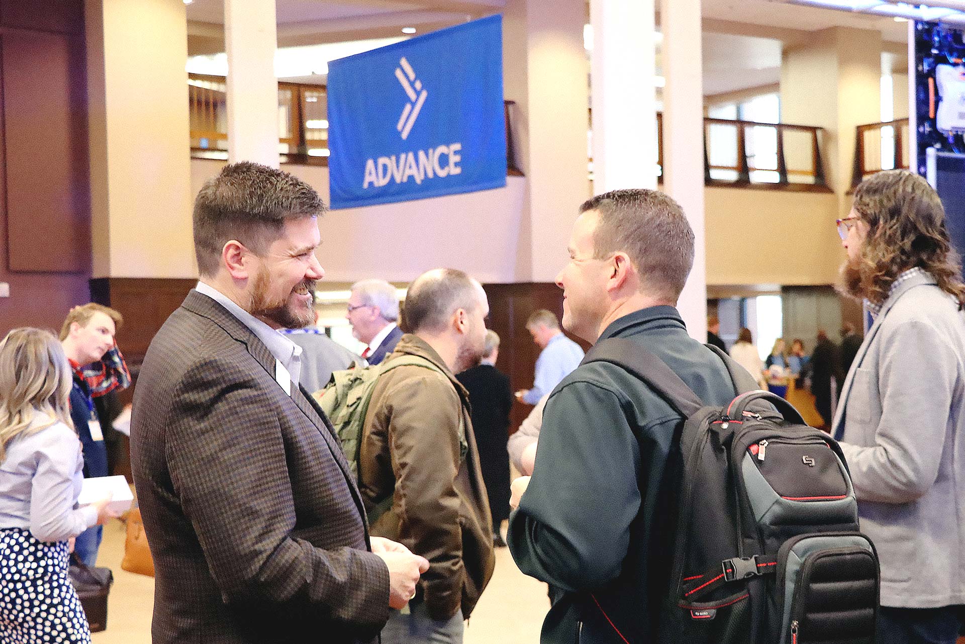 Two Oklahoma Baptists laugh, in the background is a banner using the Oklahoma Baptists logo icon.