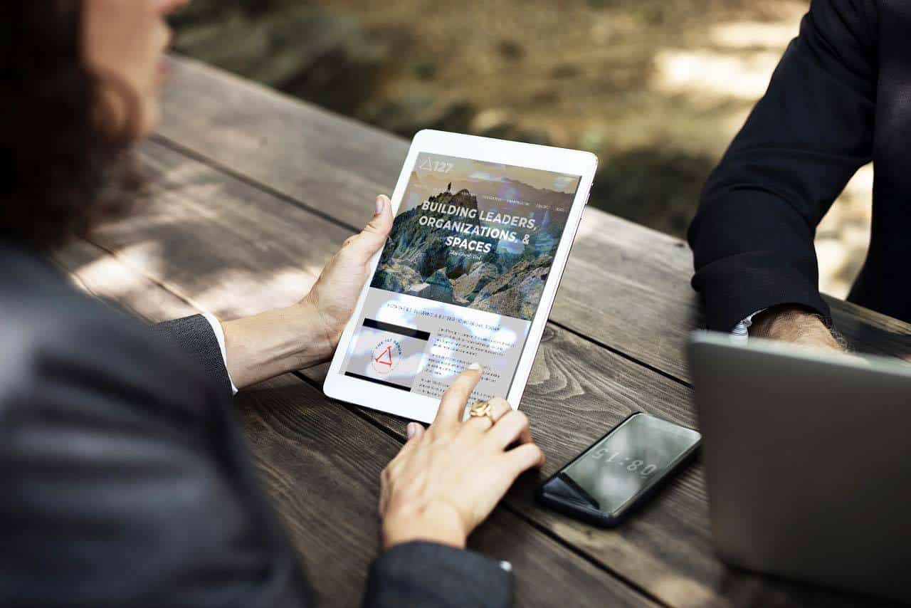 tr portfolio 127group Two people in a meeting with the 127 Group site pulled up on a tablet