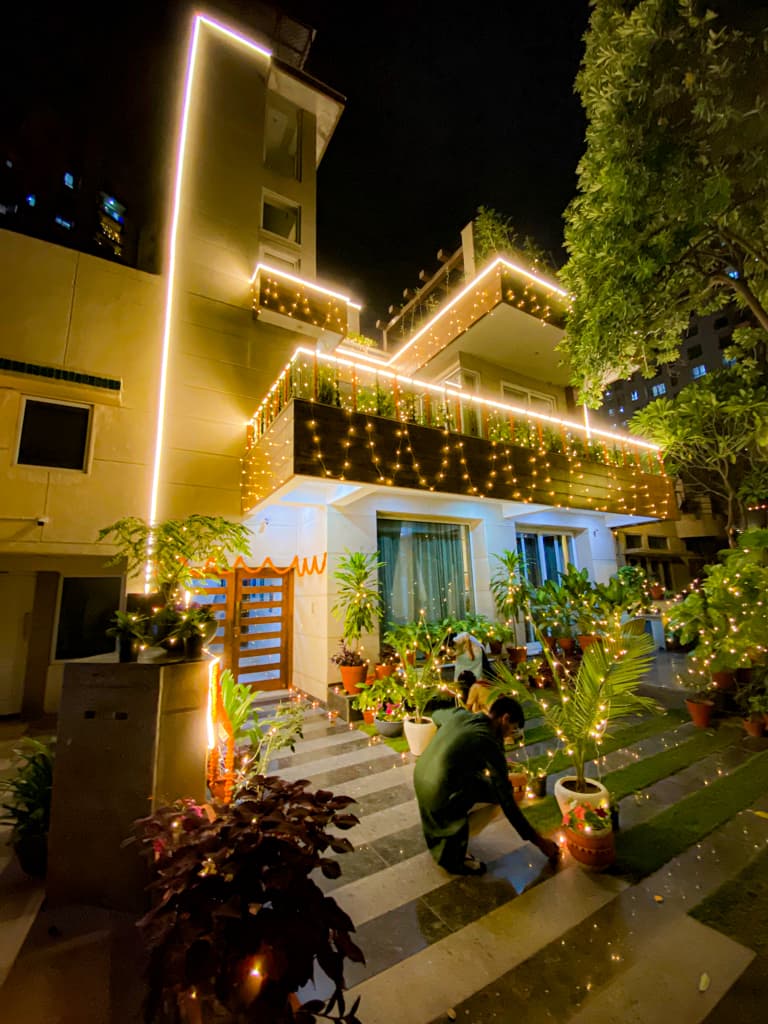 Rahul placing candles around the exterior of a house lit up with lights trimming its edges