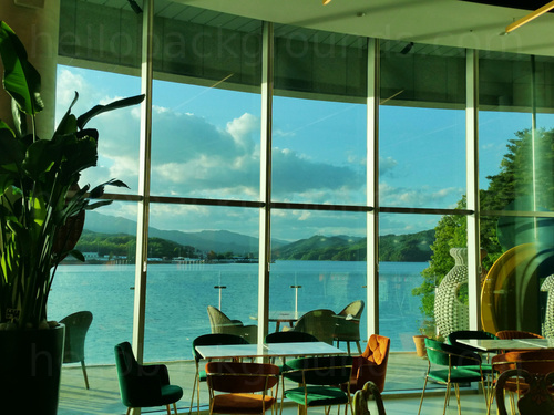 Scenic cafe interior featuring large windows with views of outside decking and mountain lake   Zoom background