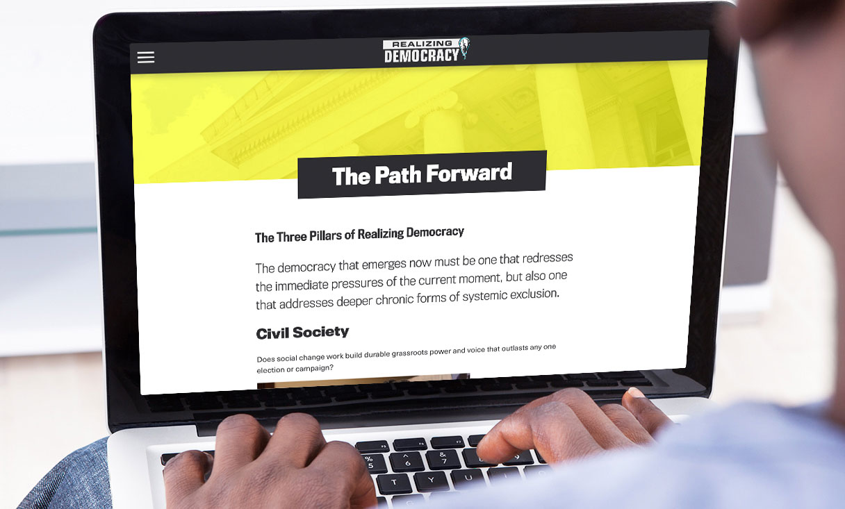 realizing democracy a path forward navigation page viewed on laptop.