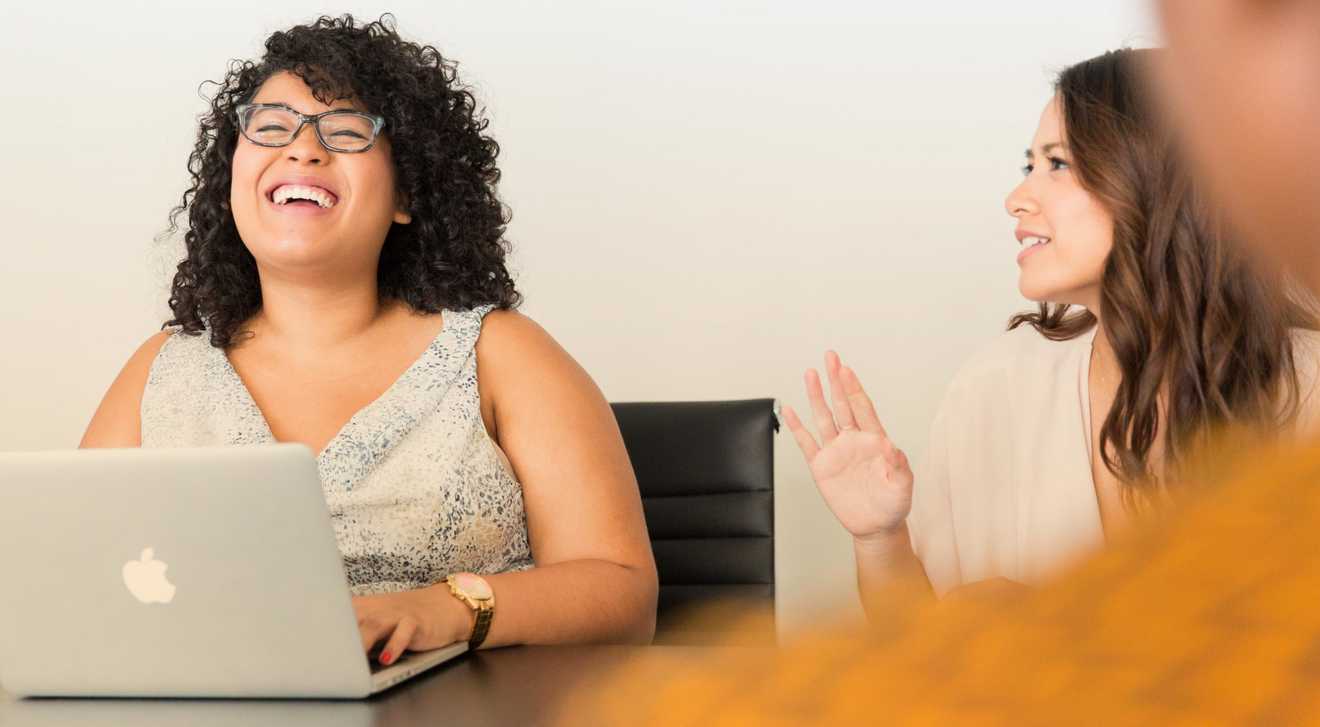 Two women laugh together at an office