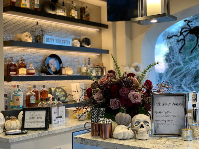 Table with purple flowers and a sparkling skull, with a drink menu and bar in the background.