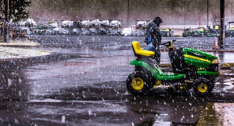 Man walking by a green riding lawn mower