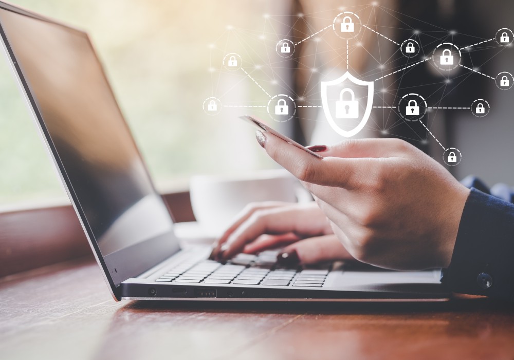 Person at laptop with a card in their hand. Symbols floating above showing locks.