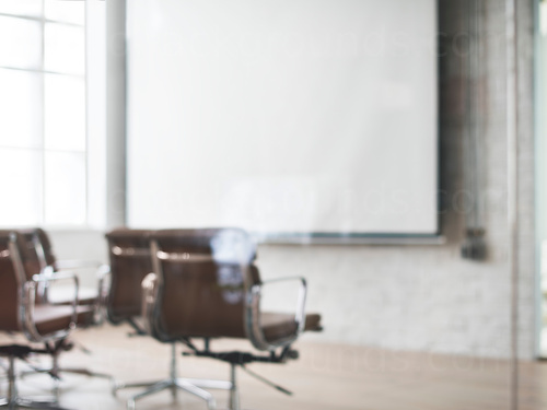 Large bricked meeting room with white walls featuring brown metal framed seating and projector screen Zoom background