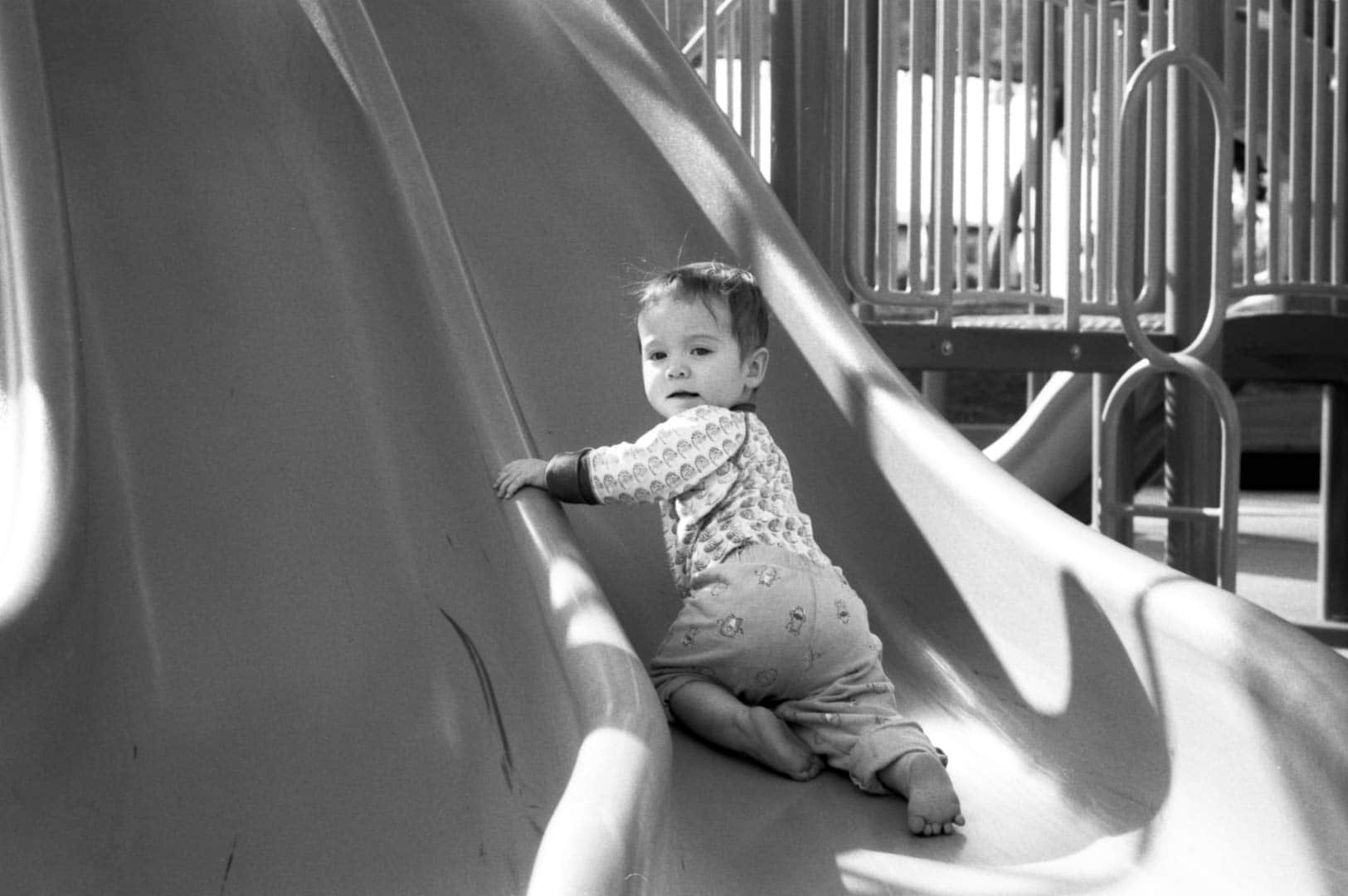 A baby trying to crawl up a slide on the playgound