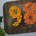 Diced pumpkin pieces arranged into the shape of a nine on the chopping board. Next to it is an eight made with chopped carrot.