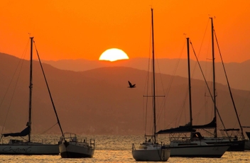 Pôr-do-sol com céu alaranjado e barcos na água