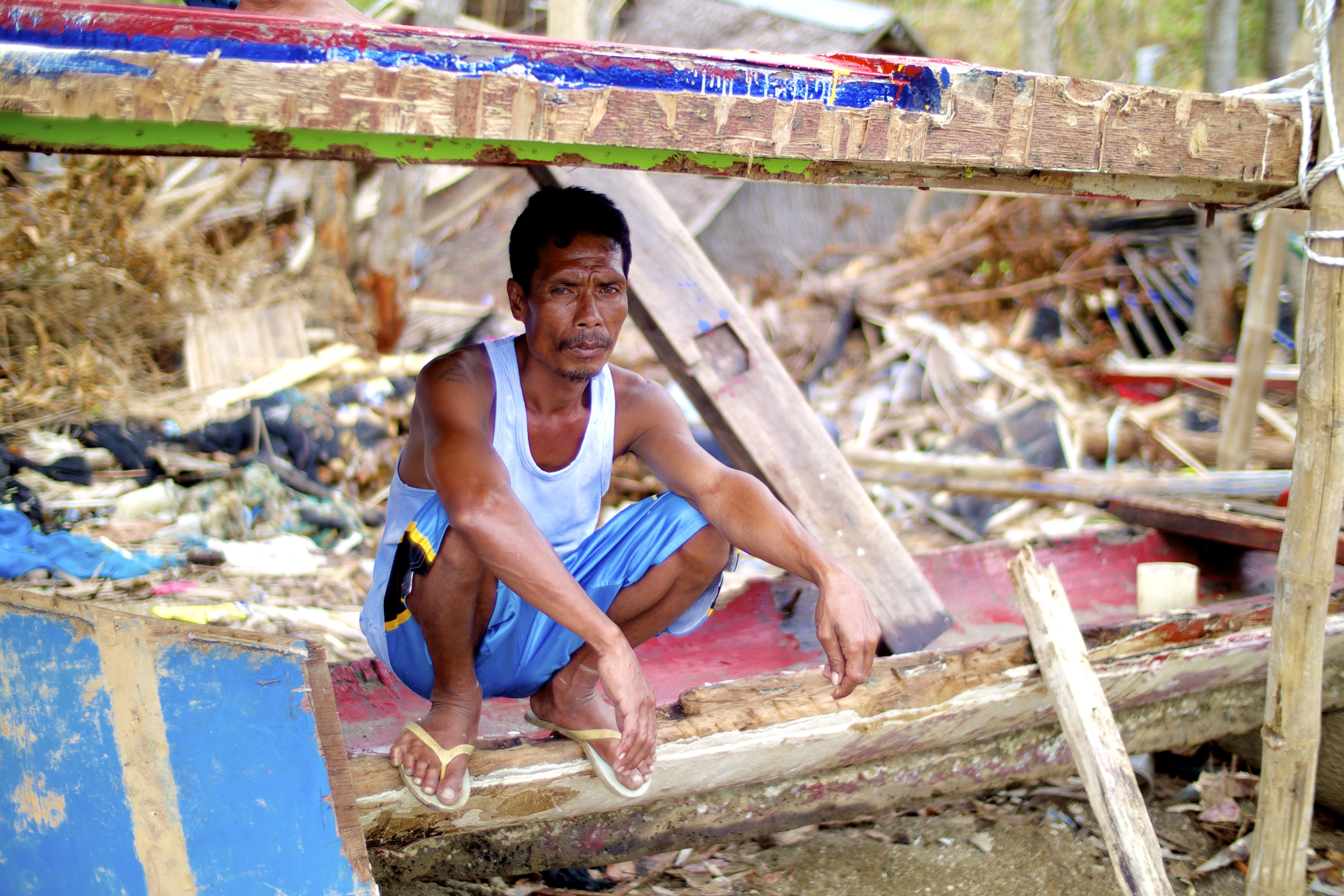 Fishing captain sits in the wreckage of the boat he and his crew relied upon for their livelihoods, damaged during Typhoon Haiyan